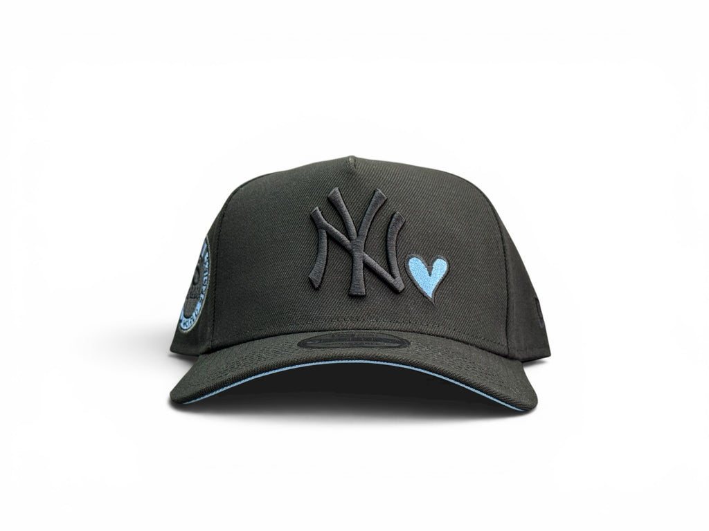 Gorra snapback JR Caps MTY negra de New York Yankees con logo bordado, detalle de corazón azul y parche lateral.